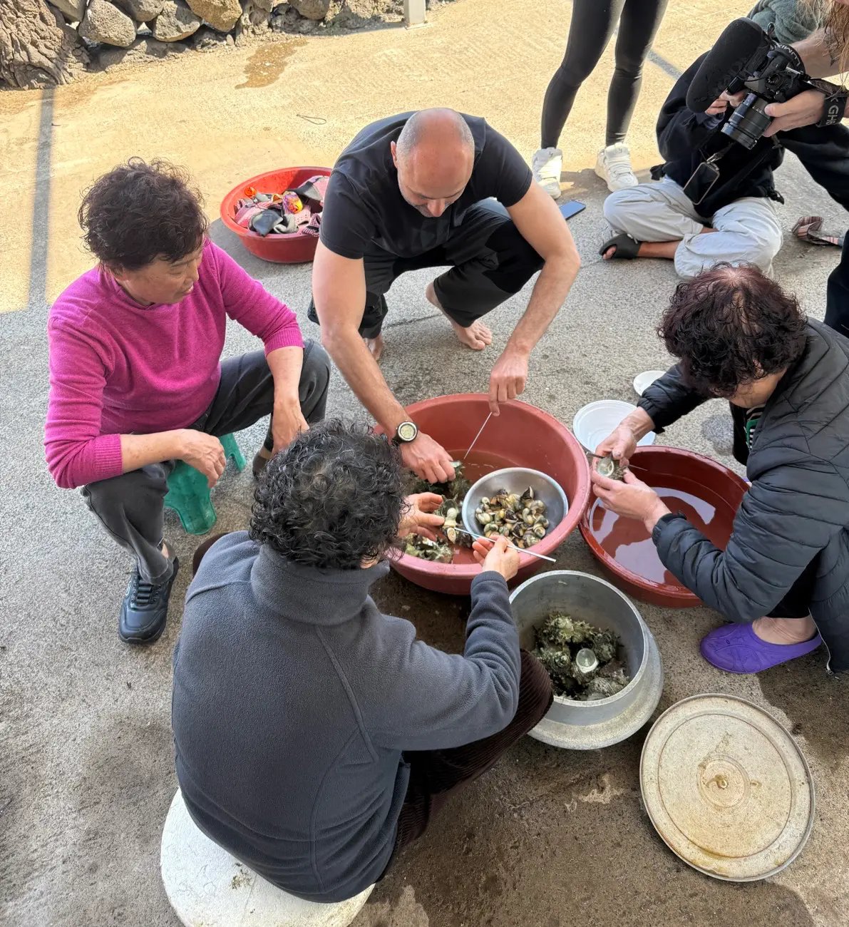 Viajeras limpiando marisco junto a dos haenyeo en Jeju